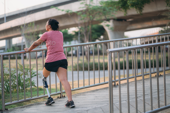 Woman wearing prosthetic equipment jogging in a park. Female walking and exercise works out outside.