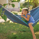 Barefoot girl bites off ripe carrot, laughing merrily while sitting in a hammock - PhotoDune Item for Sale
