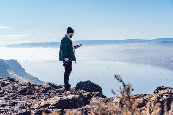 Anonymous traveler navigating with mobile phone while standing on edge