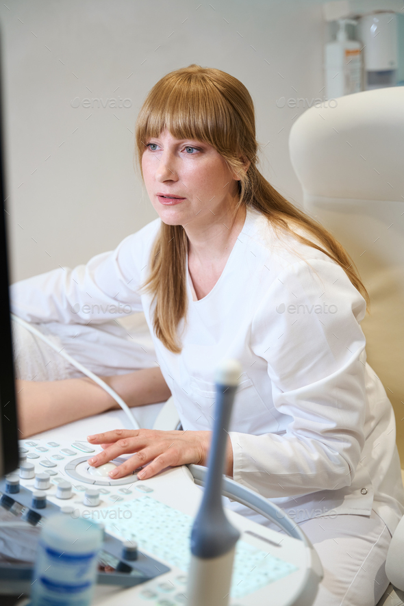 Diagnostician makes an ultrasound of the thyroid gland to patient