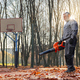 Smiling senior man removing leaves from fenced playground.  - PhotoDune Item for Sale