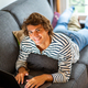 Young man relaxing on sofa at home working on laptop - PhotoDune Item for Sale