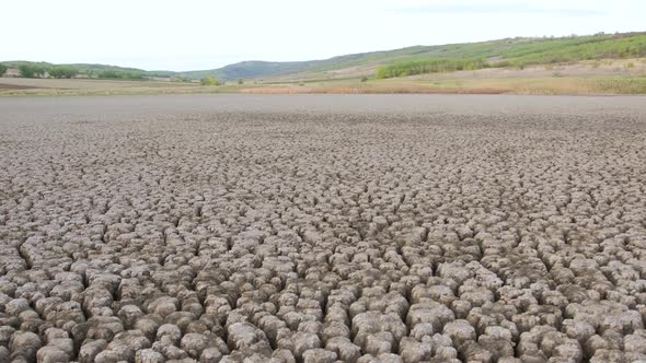 A Huge Area of a Very Dry Lake Suffering From Drought, Next To It Everything Is Green. alt