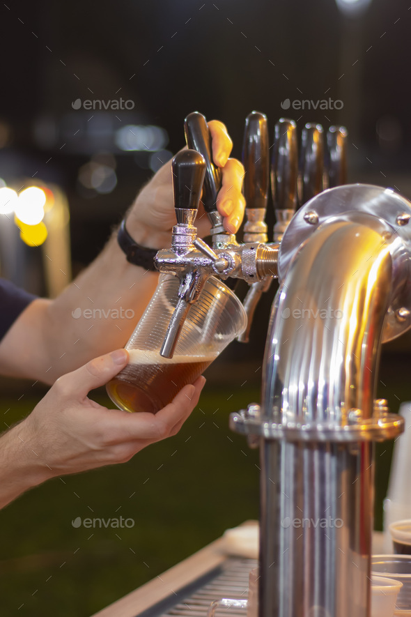 Male's hands pouring beer in a plastic cup from a kegerator Stock Photo