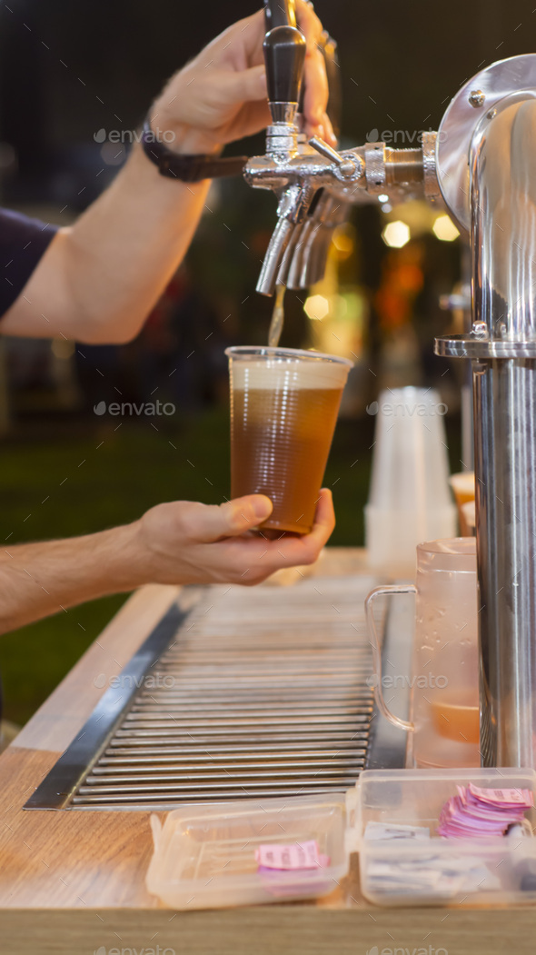 Male's hands pouring beer in a plastic cup from a kegerator Stock Photo