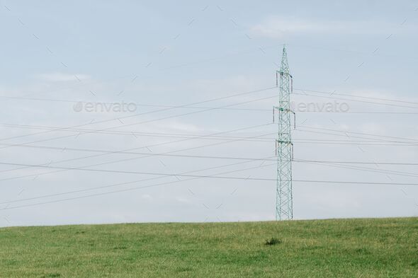 High-voltage steel pylon tower with electric lines on a rural green ...