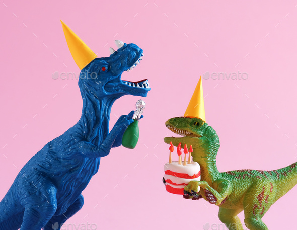 Cute plastic toy green dinosaurs in party hat with cake and champagne bottle