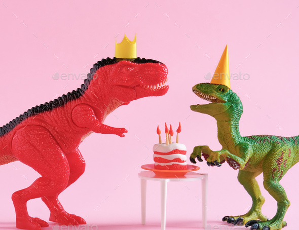 Cute happy green and red dinosaurs in birthday hats with cake with flaming candles