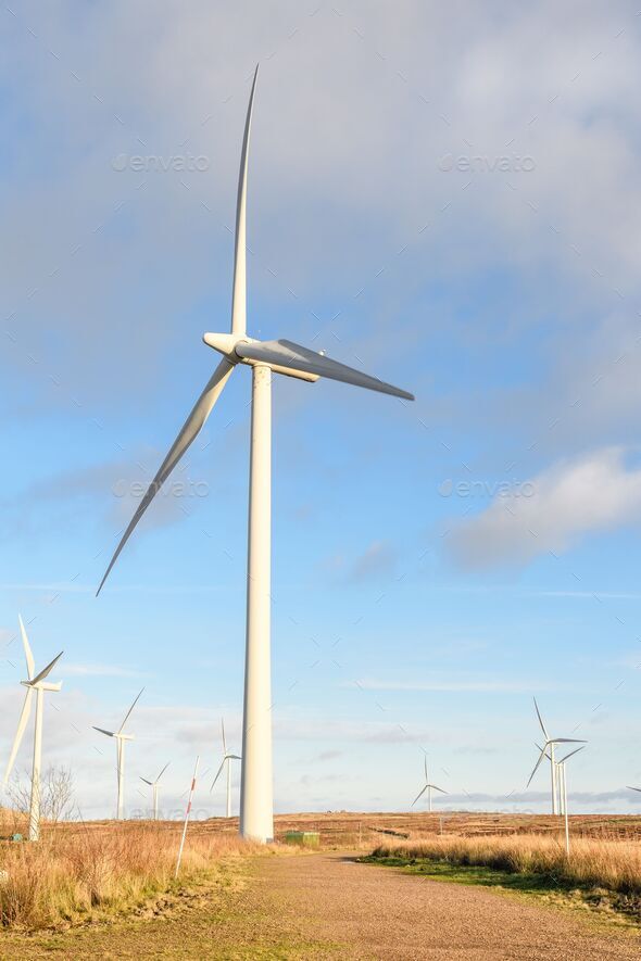 Wind turbines spinning at a wind farm against blue cloudy sky