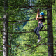 Happy young woman in helmet walking on ropes in forest park in daylight - PhotoDune Item for Sale
