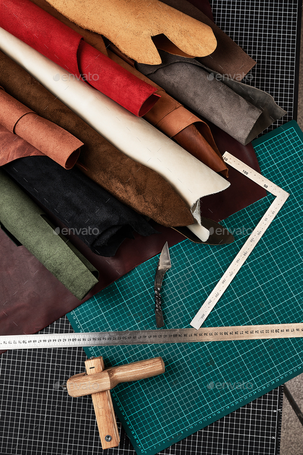 Samples of genuine leather of different colors are rolled up on a table  with mats and tools for Stock Photo by Gerain0812