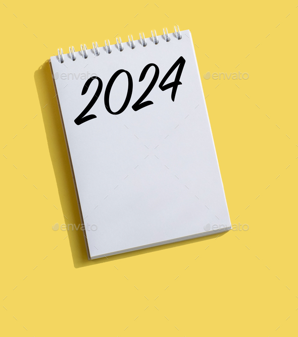 New Year 2024 written on note paper on a bright yellow background.
