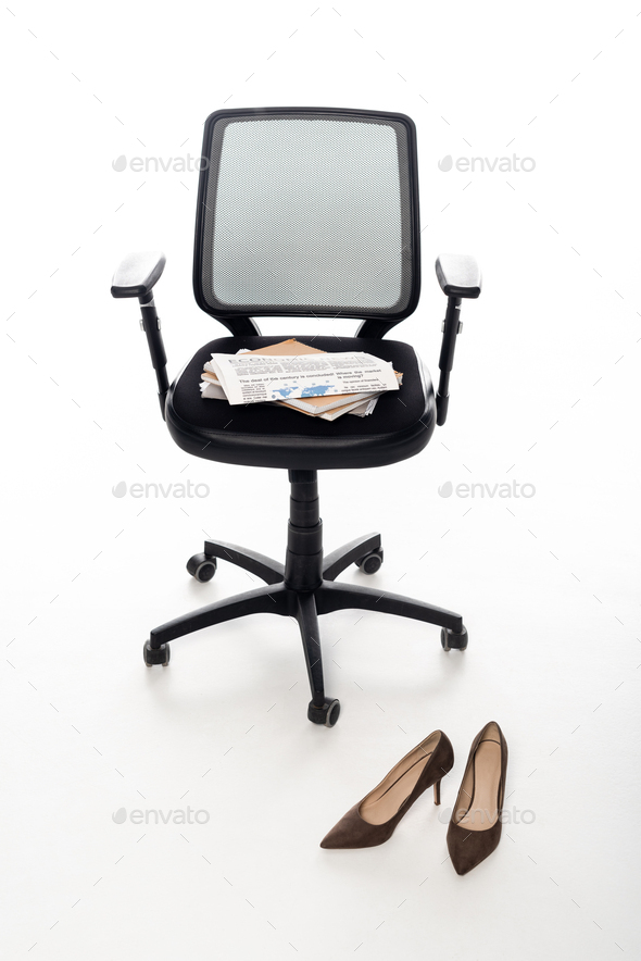Office chair with notebooks and newspaper near shoes on white background