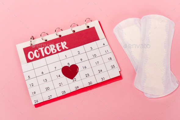 High angle view of calendar with paper heart near feminine pads on pink  background Stock Photo by LightFieldStudios