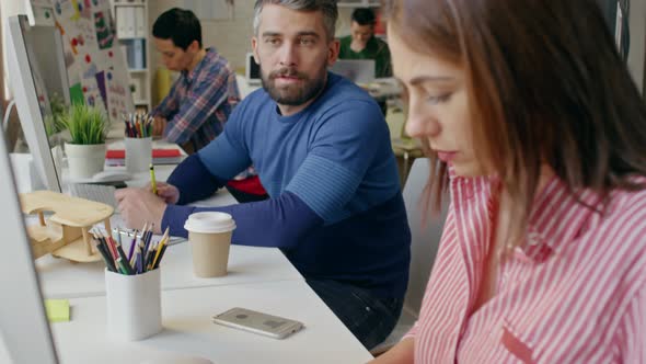 Man Making Suggestions to Typing Colleague alt