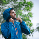 man in a raincoat in the rain in a rainy day in the park, the concept of the rainy season - PhotoDune Item for Sale