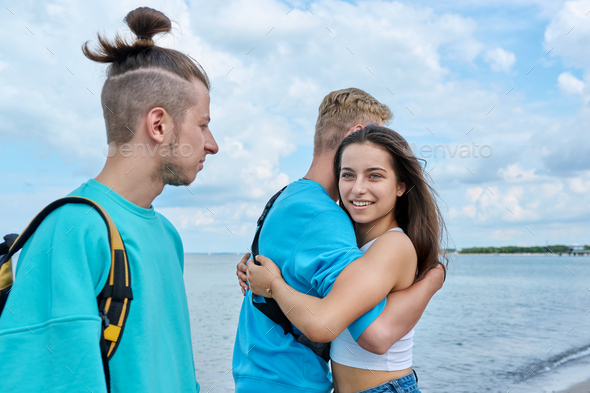 Outdoor teenage friends meeting, hugging teenagers on beach