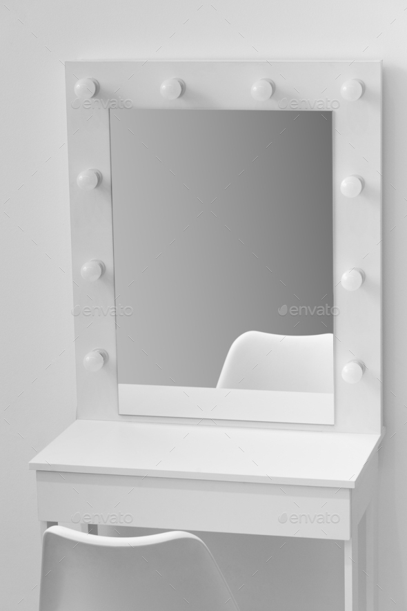 White makeup dressing table with lamps and a chair against a white wall
