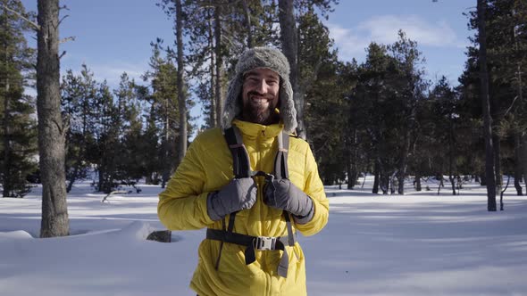 Portrait of a Young Hiker Looking Directly Into the Camera Near a Snowy Mountain Forest alt