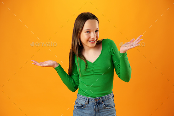 Puzzled teen girl don\'t know what to do on yellow background in studio