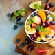 Bowl of healthy fresh fruit salad on a blue rusty background. Top view with copy space. Flat lay - PhotoDune Item for Sale