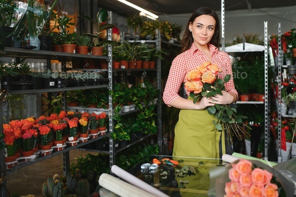 Young beautiful woman florist make bouquet of flowers at flower shop