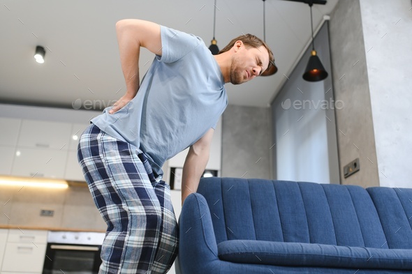 Handsome man lifting sofa and feeling pain. man droped sofa because of painful back