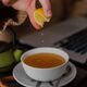 Closeup of a girl squeezing lemon into a cup of tea at a bar with cinnamon sticks beside it - PhotoDune Item for Sale