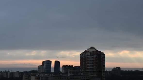 Urban Skyline with Silhouettes of Highrise Buildings and Construction Cranes Against Cloudy Sky