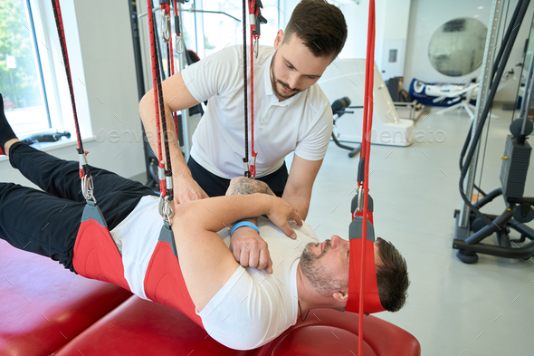 Adult person doing sling training exercise supervised by