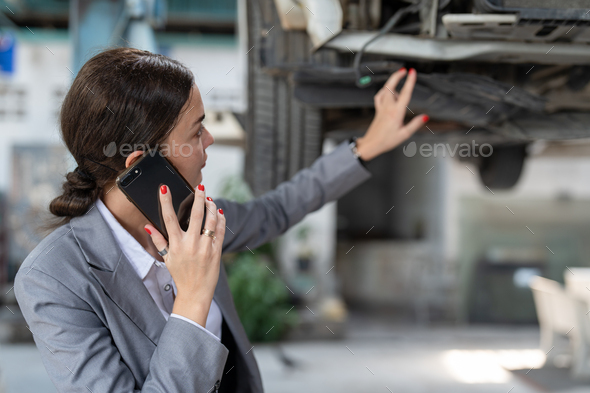 Businesswoman client using smartphone talking with agent claim insurance her car at garage service.