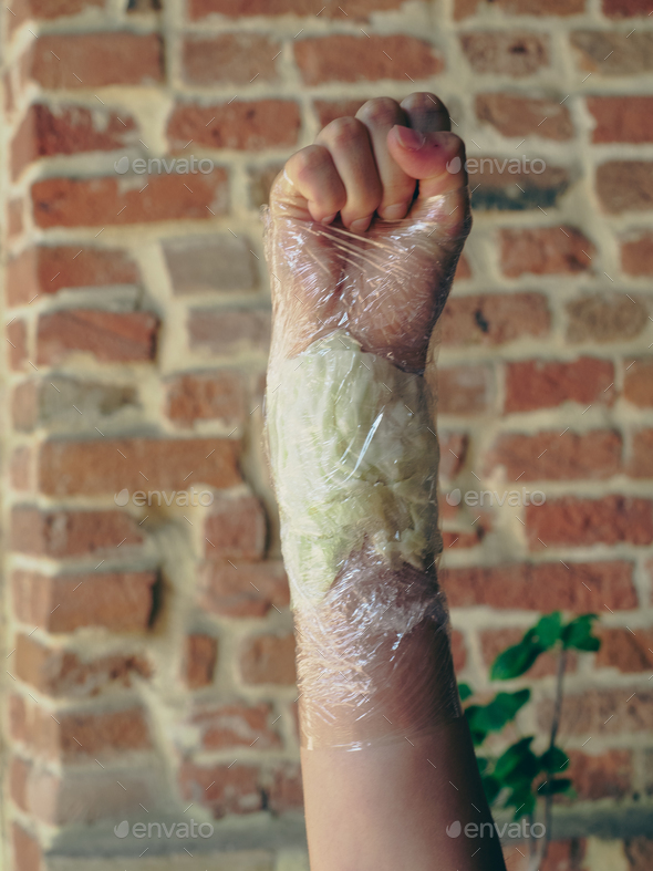 woman wrist wrapped with cabbage leaves compress for anti inflammatory pain relief.