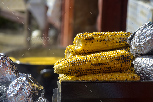 Freshly baked corn on fire. Sale of freshly baked corn at fair. Close-up. Selective focus.