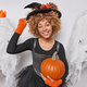 Halloween celebration on 31st October. Positive happy woman adorns herself in festive attire as she - PhotoDune Item for Sale