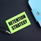 colored pen, book and paper with the word retention strategy.  - PhotoDune Item for Sale