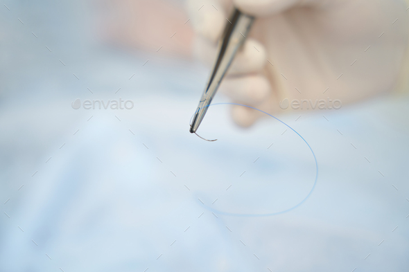 Man holds in his hand a surgical needle