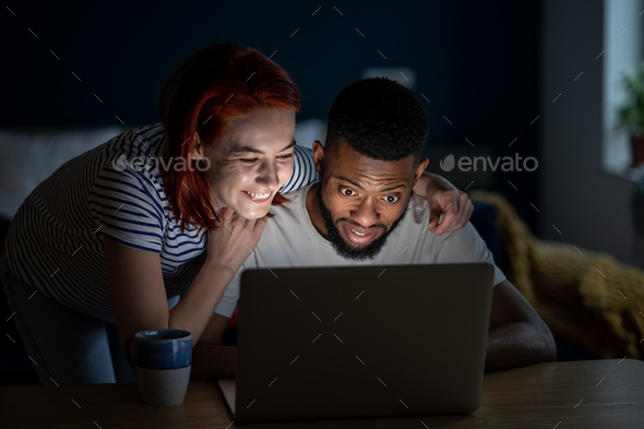 Happy romantic couple watching videos on Internet from laptop laugh smile enjoy funny comedy movie