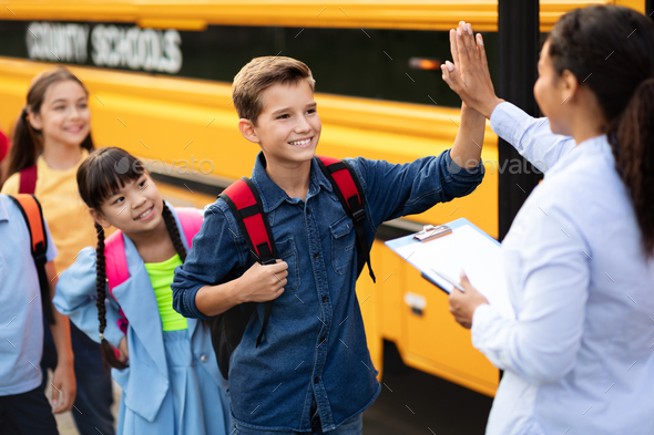 Black Female Teacher Giving High Five To Boy Entering School Bus Stock ...