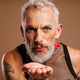 Bearded mature gay man with stage make-up blowing a kiss against brown background - PhotoDune Item for Sale