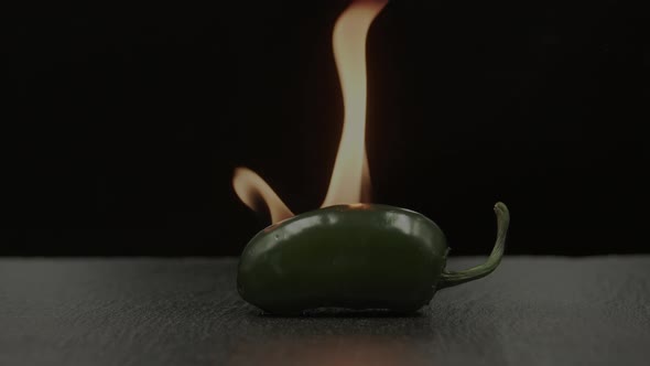 Green chili Jalapeno on fire on black background