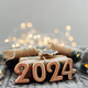 Christmas and New Year Greeting Card. Number 2024 on knitted background. Holiday lights bokeh - PhotoDune Item for Sale