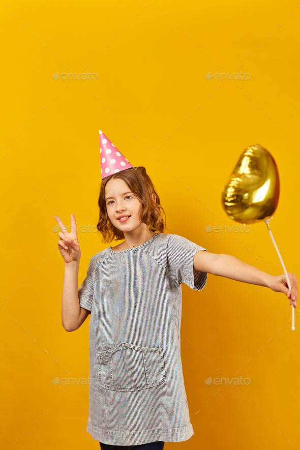 Cheerful, positive ten years birthday girl in party hat