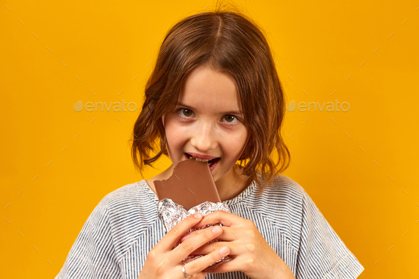 Pretty teen girl eat, bites a chocolate bar