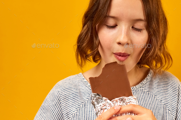 Pretty teen girl eat, bites a chocolate bar