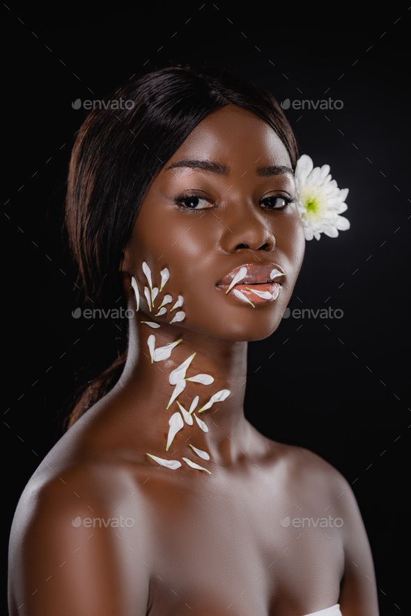 naked african american woman with white chrysanthemum in hair and petals on neck and lips