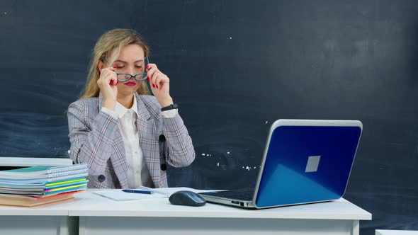 School Teacher Sits at Desk Checks Homework alt