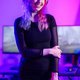 Portrait of a smiling e-sport gamer girl in front of her computer in her colorful gaming room - PhotoDune Item for Sale