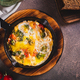Frying pan with scrambled eggs with broccoli and tomatoes on a wooden board top view - PhotoDune Item for Sale