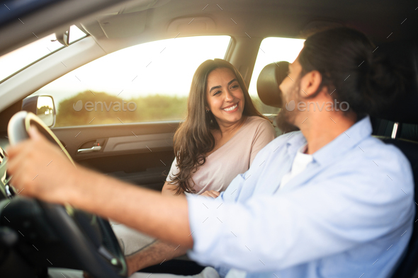 Happy latin couple enjoying car ride sitting in auto inside, going on trip, selective focus on