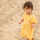 Little toddler girl in yellow dress walking on sandy beach at summer time, childhood memories - PhotoDune Item for Sale